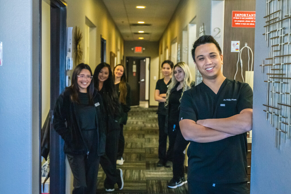 happy dental employees standing in a dental office hallway smiling